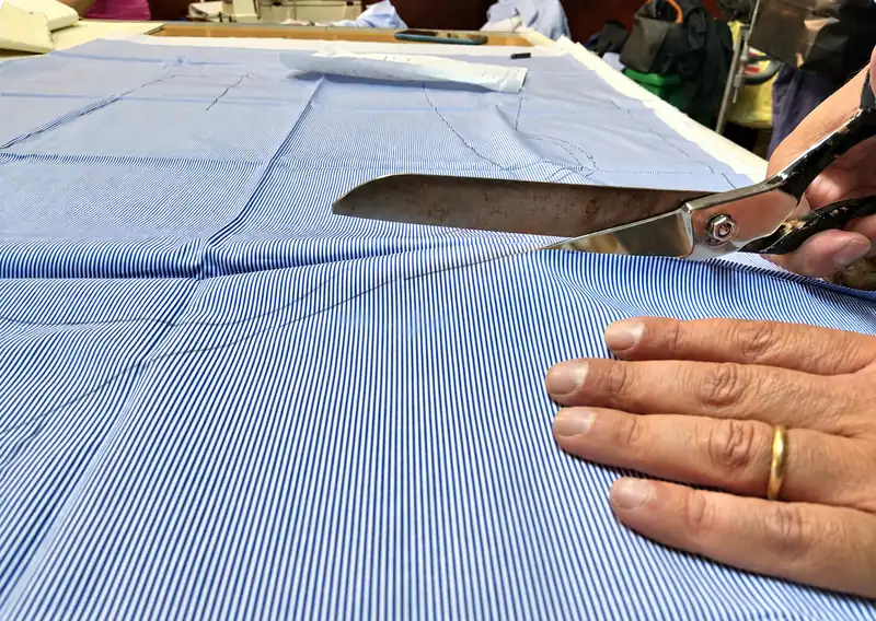 Il taglio di una camicia a righe azzurre, nel laboratorio di Antonio Gigliotti.